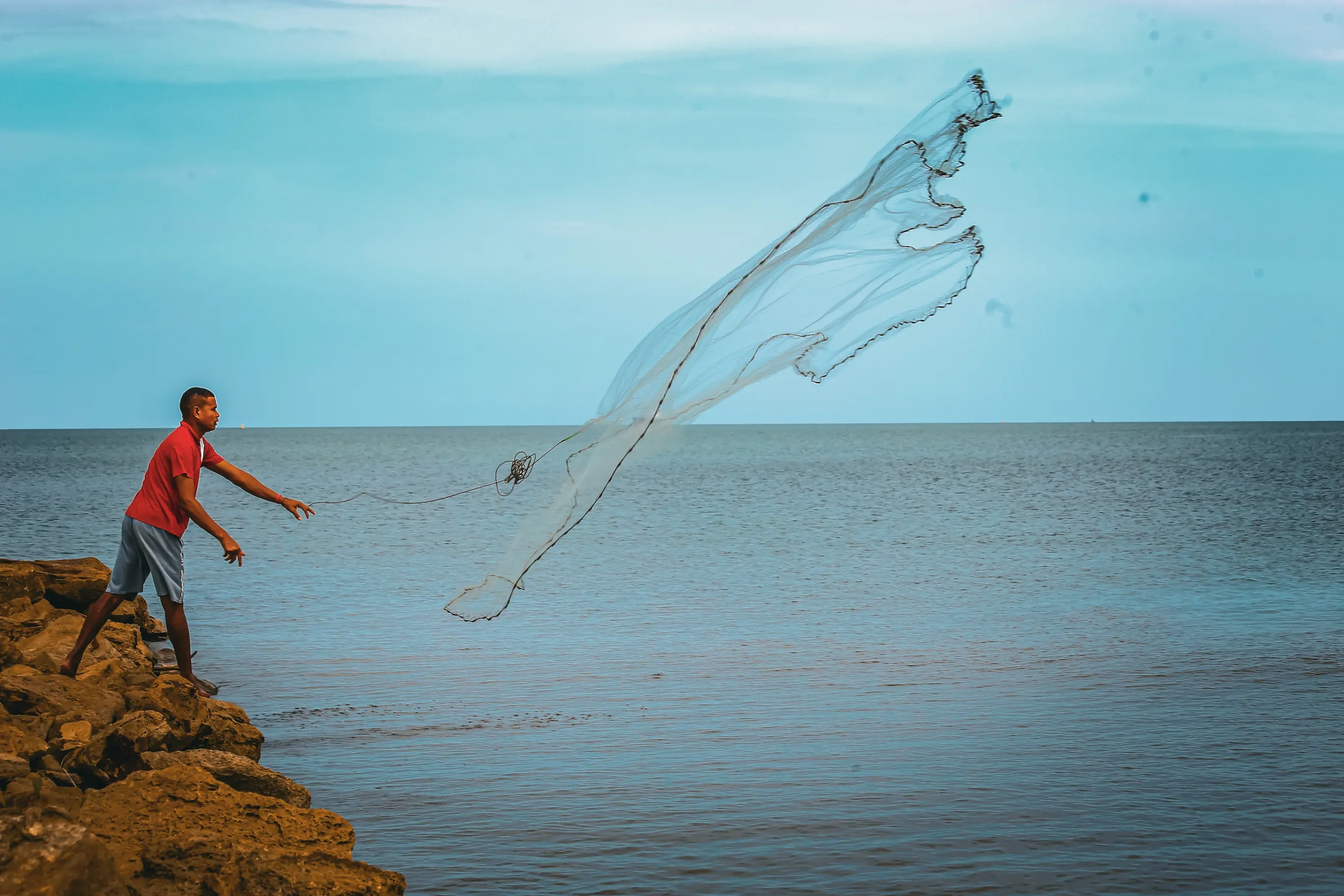 Pescadores tradicionales en una canoa sobre un cuerpo de agua tranquilo, rodeados de abundante vegetación. Refleja la vida y el sustento en los ecosistemas acuáticos de Sucre.