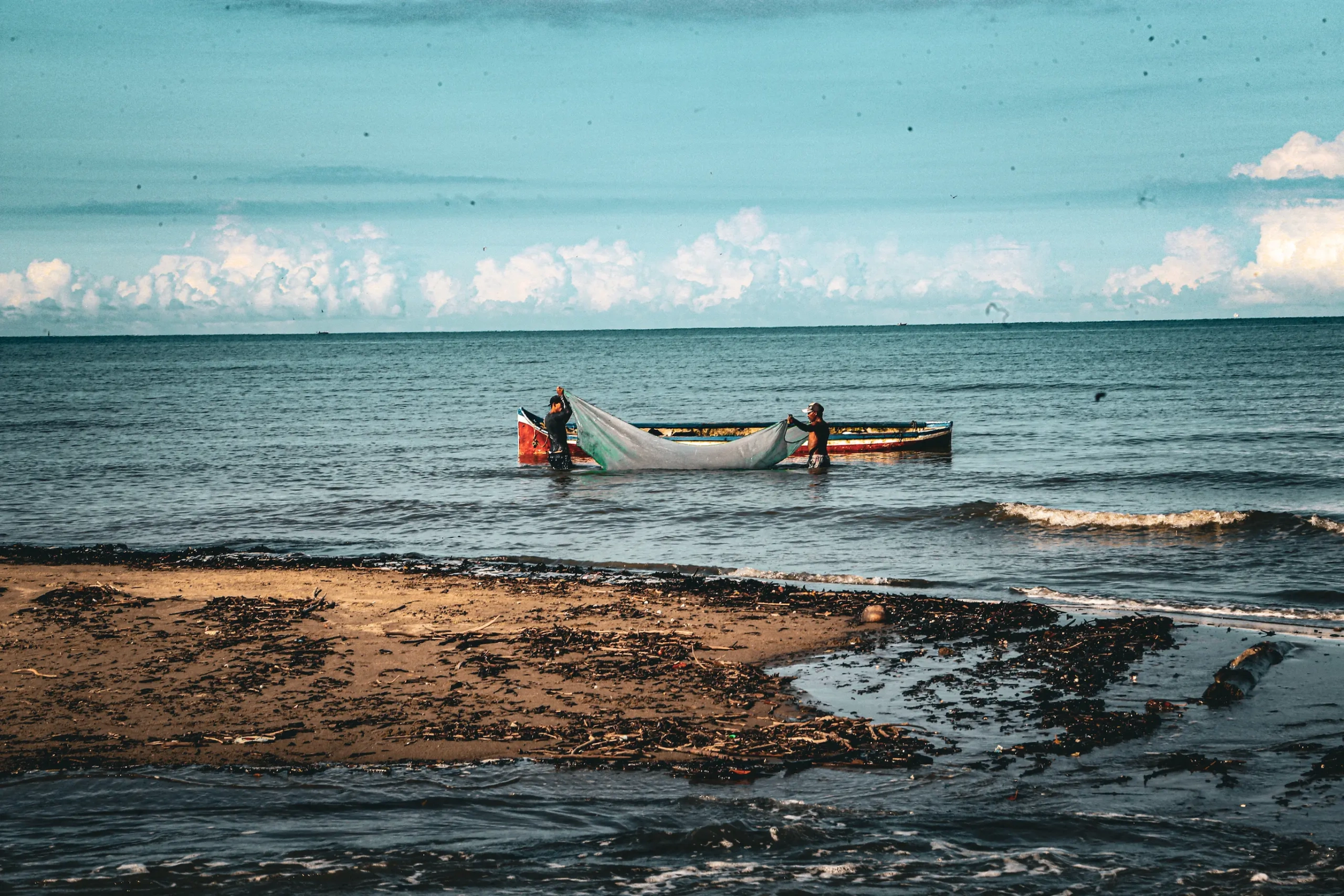 Grupo de pescadores tradicionales en una embarcación artesanal en Sucre, Colombia, en su faena diaria, rodeados de vegetación acuática en un humedal o ciénaga.
